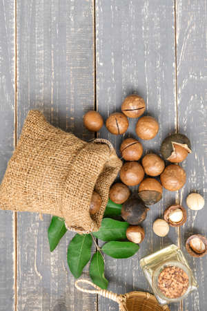Organic Macadamia nut on wooden table - vintage filter, Closeup view of natural macadamia oil and Macadamia nuts on wooden board. Healthy productの写真素材
