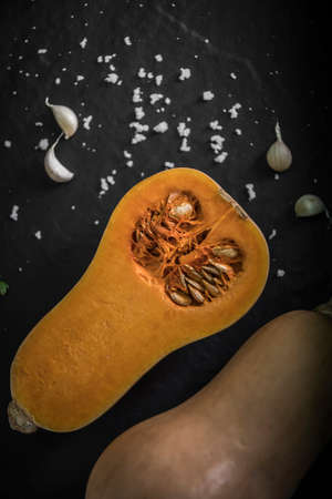 organic butternut squash with spices and ingredients for making on a black slate, Pumpkin pieces, background.Top view with copy space.の写真素材