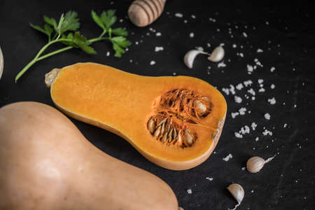 organic butternut squash with spices and ingredients for making on a black slate, Pumpkin pieces, background.Top view with copy space.の写真素材