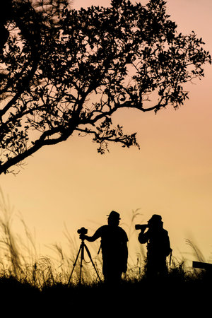 silhouette of photographer taking picture of landscape during sunrise.