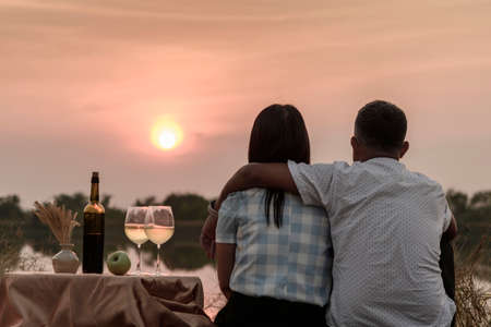 Happy life moments. Couple enjoying the sunset while having a glass of wine.の写真素材