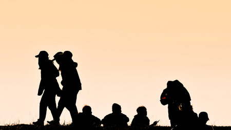Silhouettes of hikers with backpacks enjoying sunset view from top of a mountain, Silhouette...