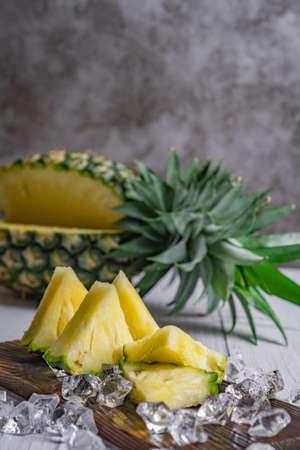 Pineapple cocktail or juice with ice and pineapples on a dark background, Wooden board with fresh sliced pineapple on tableの写真素材