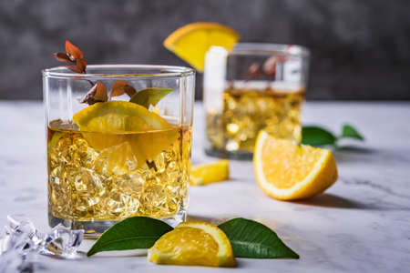 Fresh cocktail with orange, mint and ice, selective focus, Glass of the orange alcoholic drink with ice and slice of orange peel on the dark background.の写真素材