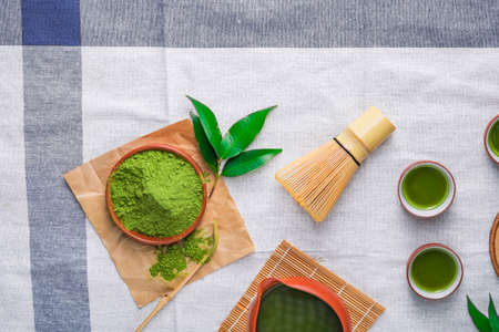 Green tea powder with leaf in ceramic dish on the table, Japanese wire whisk made of bamboo for matcha tea ceremony.の写真素材