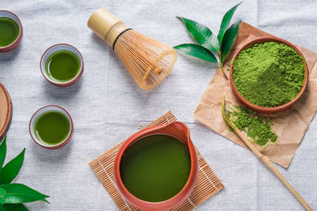 Green tea powder with leaf in ceramic dish on the table, Japanese wire whisk made of bamboo for matcha tea ceremony.の写真素材