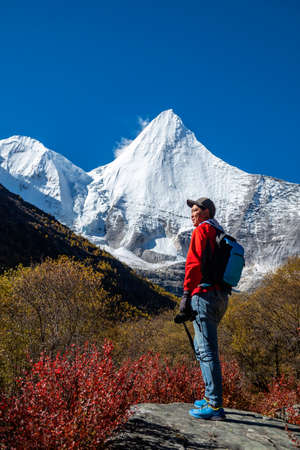 Happy tourist at top of mountain at outdoors during a hike the summit of mountain peak. Success freedom and happiness achievement in mountains. Active sport concept on the trek in The last Shangri la, Daocheng-yading, Beautiful Scenic of Yading Natural Reのeditorial素材
