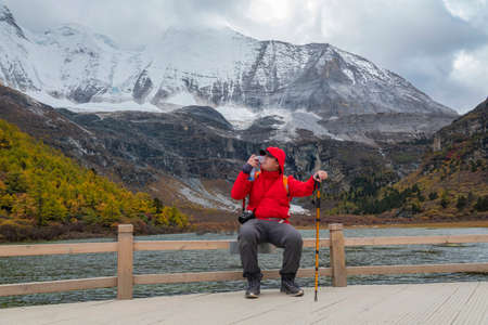 Happy tourist at top of mountain peak. Success freedom  in mountains. Active sport concept on the trek in The last Shangri la, Daocheng-yading, Beautiful Scenic of Yading Natural Reserve, Sichuan, China.のeditorial素材