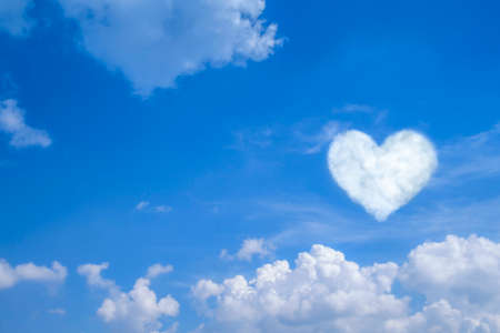 Blue sky with white clouds, clear blue sky with heart shaped clouds with space for text background.の写真素材