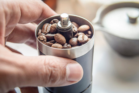 Coffee beans in a hand grinder, Pour roasted coffee beans into a manual coffee grinder.の写真素材