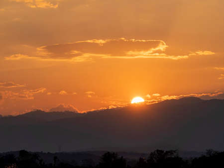 Beautiful sunset in the mountains. Landscape with sun shining through orange clouds, Sun setting over hills,  sunset on mountains.の写真素材