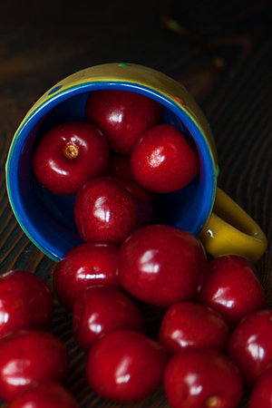 Fresh cherries in jar on the wooden background. Selective focus. Focus on the right cherries in...