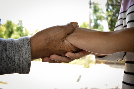 Close up granddaughter takes care of the health sick grandmother at home by holding hands. Lifestyle...