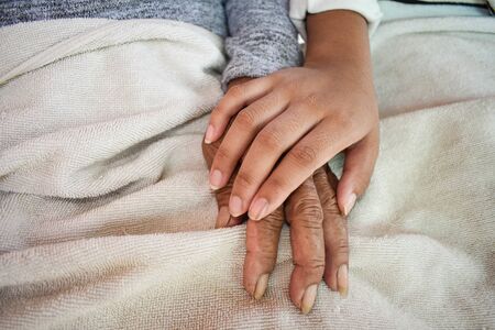 Close up granddaughter takes care of the health sick grandmother at home by holding hands. Lifestyle support the love of the family.の写真素材