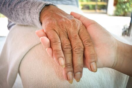 Close up granddaughter takes care of the health sick grandmother at home by holding hands. Lifestyle support the love of the family.の写真素材
