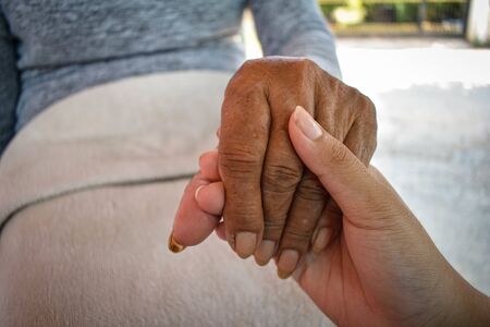 Close up granddaughter takes care of the health sick grandmother at home by holding hands. Lifestyle support the love of the family.の写真素材