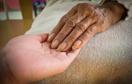 hand of the sick old woman rests on the lap. Mental health care at home.の写真素材