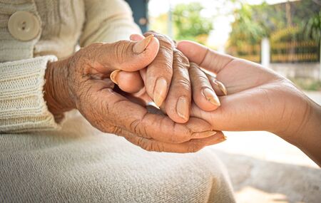 Close up granddaughter takes care of the health sick grandmother at home by holding hands. Lifestyle support the love of the family.の写真素材