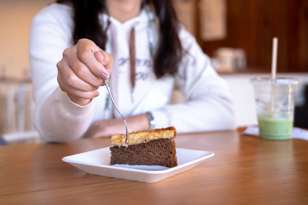 Asian woman eating piece of diet cake. Lifestyle of Happy young female smiled and enjoyed eating dessert at coffee shop. Diet cake concept.の写真素材