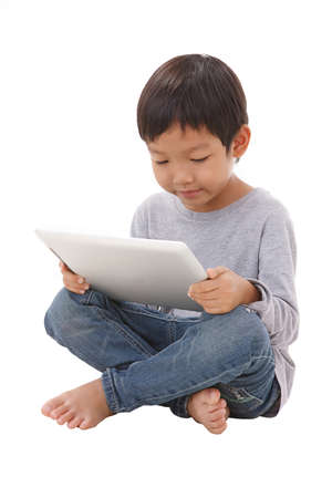 Boy using tablet while sitting on the floorの写真素材