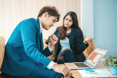Angry and unhappy asian businesswoman arguing with businessman about work failure at office, executives having conflict over responsibility for bad work results in office with man  in foreground.の写真素材