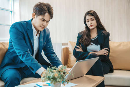 Asian serious businessman and angry businesswoman arguing  about work failure at workplace, executives having conflict over responsibility for bad work results in officeの写真素材