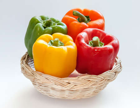 4 colors capsicum or sweet pepper in a basket on white backgroundの写真素材