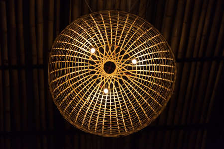 Bamboo woven lamp with light turning onの写真素材