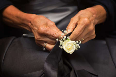 Hands of mother who sew flowers on the groomの写真素材