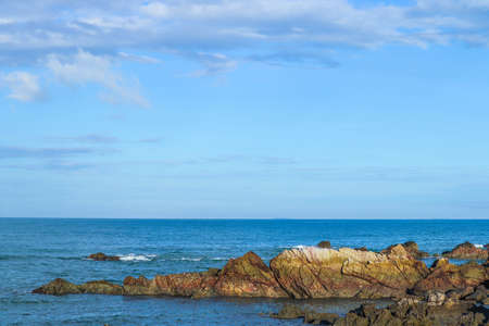 The water of a wave falling on a rock, with the horizon of the sea, the water and the blue sky.の写真素材