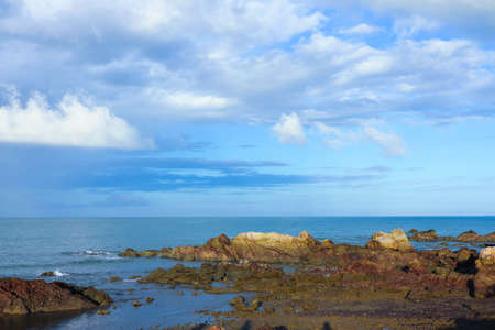 The water of a wave falling on a rock, with the horizon of the sea, the water and the blue sky.の写真素材