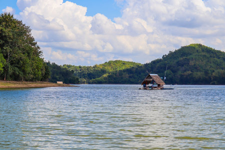 The raft in the dam. middle of the water There is a small house. There is a small boat. In the...