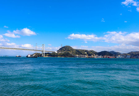 Kanmon Straits between Fukuoka and Yamaguchi Prefectures and the view of the Kanmon Bridge connecting the straits and the blue skyの写真素材