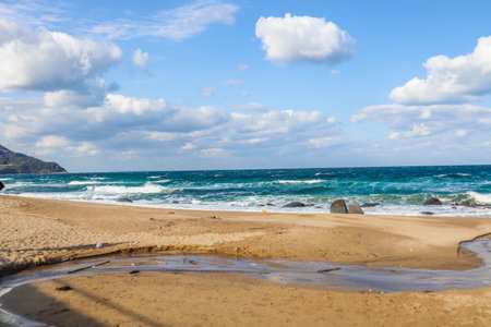 Beautiful empty sand beach with good waves on a nice sunny day, clouds in the skyの写真素材
