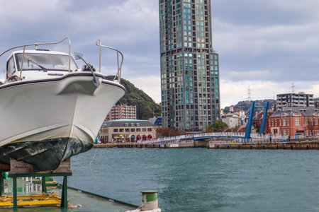 Scenic Waterfront View Featuring Moored Boat and Urban Skylineの写真素材