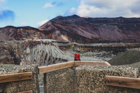 Red warning light at a volcano observation point with a dramatic view of layered volcanic terrain in the background.の写真素材