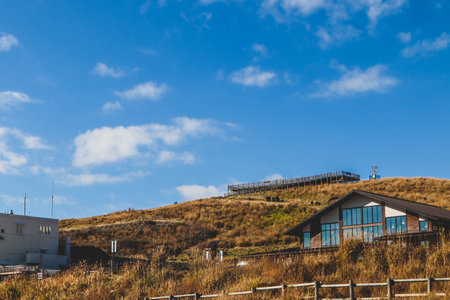 A cozy modern cabin on a grassy hill with clear blue sky, peaceful countryside scenery ideal for travel and nature concepts.の写真素材