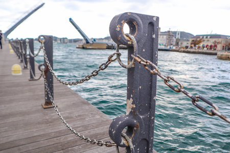 Rusty chain fence on pier with drawbridge in background.の写真素材