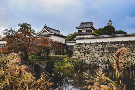 Historic Japanese Fortress with Stone Walls and Seasonal Foliageの写真素材