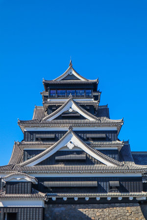 Historic Kumamoto Castle in Japan with traditional architecture against a clear blue sky.の写真素材