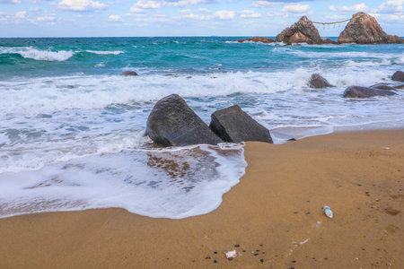 Scenic View of Meoto Iwa Rocks Tied with Shimenawa Rope, Under Cloudy Blue Skyの写真素材