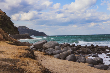 Waves Crashing Against Coastal Boulders on Windy Dayの写真素材