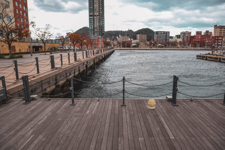 Empty Wooden Boardwalk along the Seaside Promenade with Cityscape and Mountain in Background, Japanの写真素材