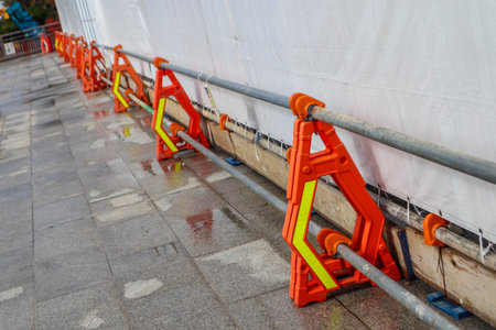 Temporary Construction Fence with Reflective Safety Markings Along Sidewalk in Cityの写真素材