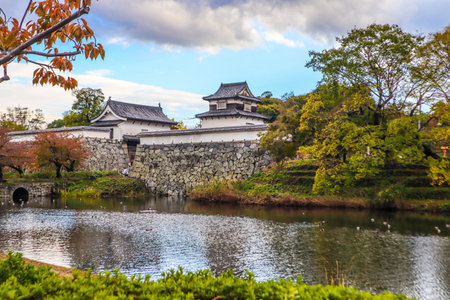 Historic Japanese Fortress with Stone Walls and Seasonal Foliageの写真素材