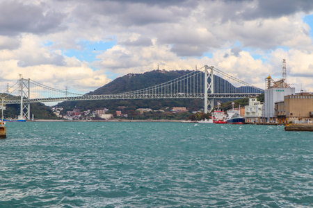 Long-Span Bridge Over Choppy Water with Cargo Ships and Industrial Port Backgroundの写真素材