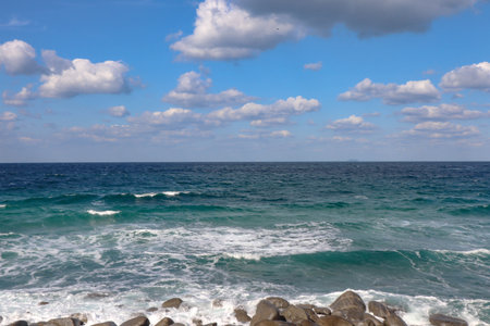 Waves Crashing Against Coastal Boulders on Windy Dayの写真素材