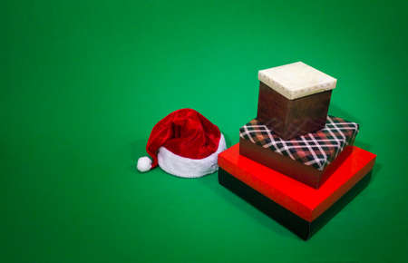 A few gifts by Santa's hat in a green background