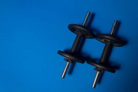 Two iron dumbbells seem from above, side by side, against a blue backgroundの写真素材
