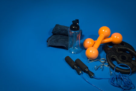 Some equipment for exercising, alongside a towel and a bottle, against a blue backgroundの写真素材